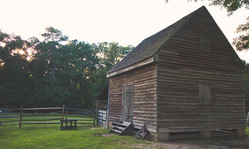 Free A weathered wooden cabin set amid green pastures and a wooden fence at dusk. Stock Photo