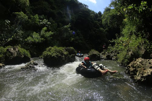 Free Orang Yang Mengendarai Cincin Tiup Hitam Di Perairan Dekat Gunung Stock Photo