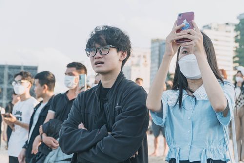 Free Crowd of people outdoors, some wearing masks and taking photos with smartphones. Stock Photo