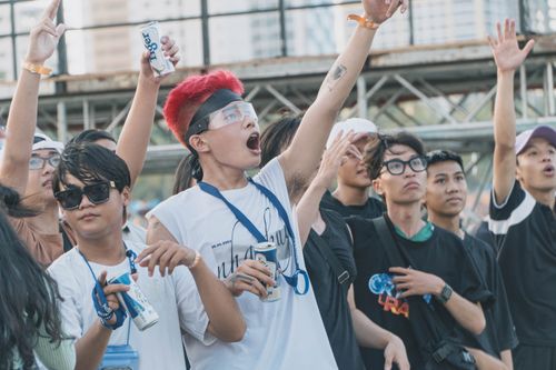 Free A lively group of young adults enthusiastically enjoy an outdoor music festival, raising their hands and having fun. Stock Photo
