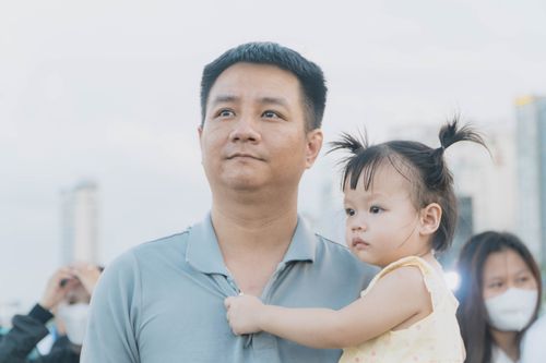 Free A father holding his toddler daughter amidst an urban landscape. Stock Photo