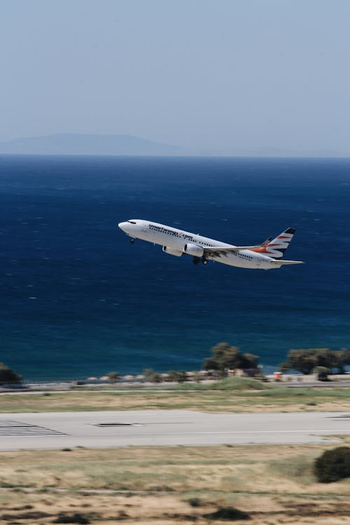 Free White Airplane Flying over the Sea Stock Photo