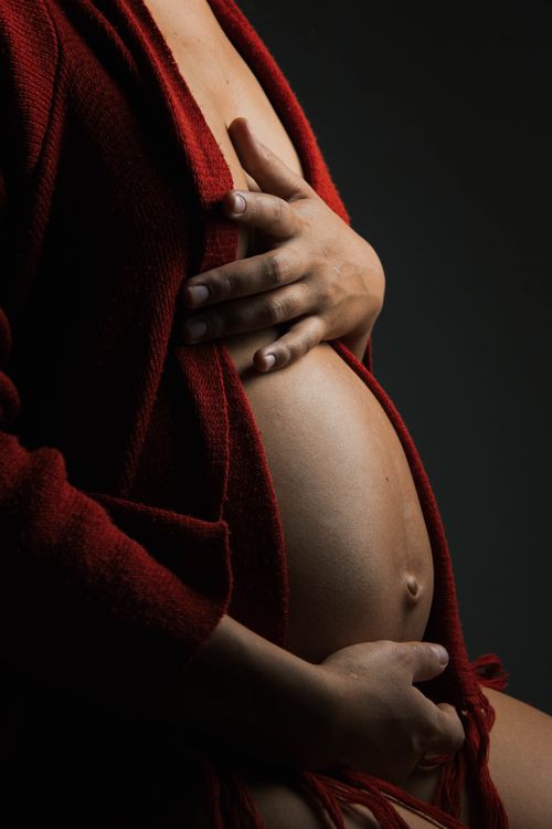 Free Artistic close-up of a pregnant woman in a red robe, highlighting expectant beauty. Stock Photo