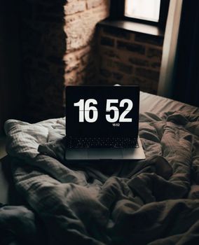 A cozy bedroom in İstanbul with a laptop showing 16:52 on the bed, creating a relaxed atmosphere.