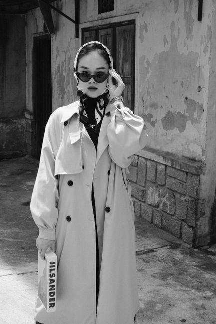 Elegant woman in a headscarf and sunglasses posing outdoors.