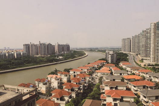 Aerial view of cityscape, showcasing modern buildings and a winding river on a sunny day.