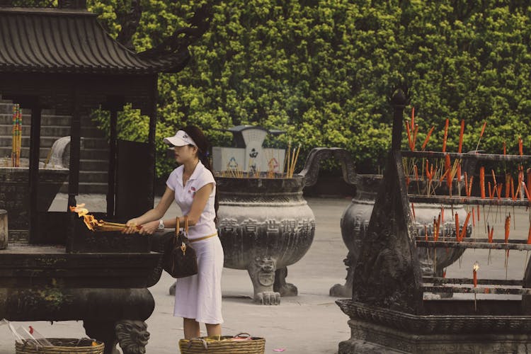 Woman In White Shirt Lighting Incense Sticks