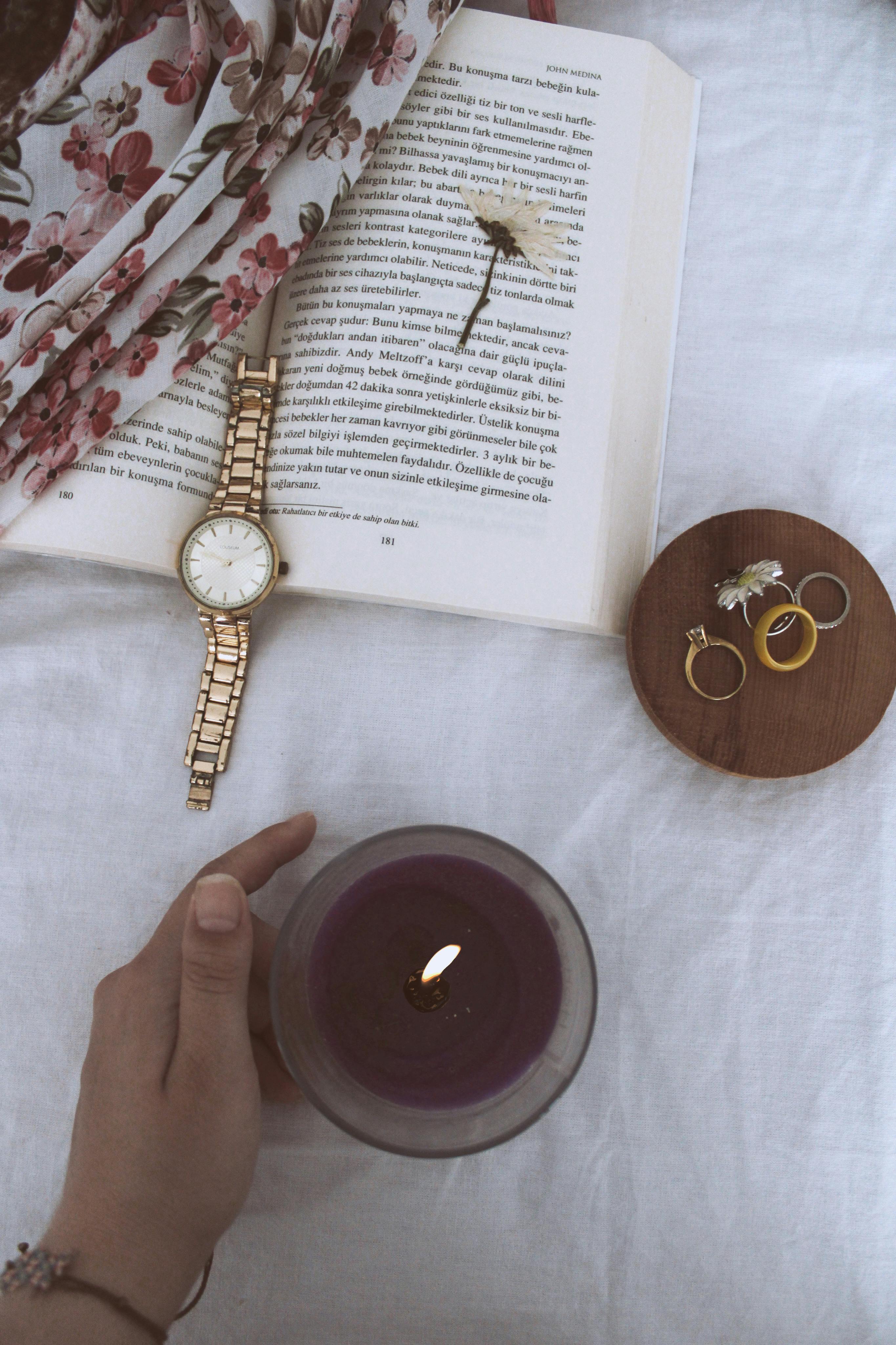 lighted candle near jewelries on white surface