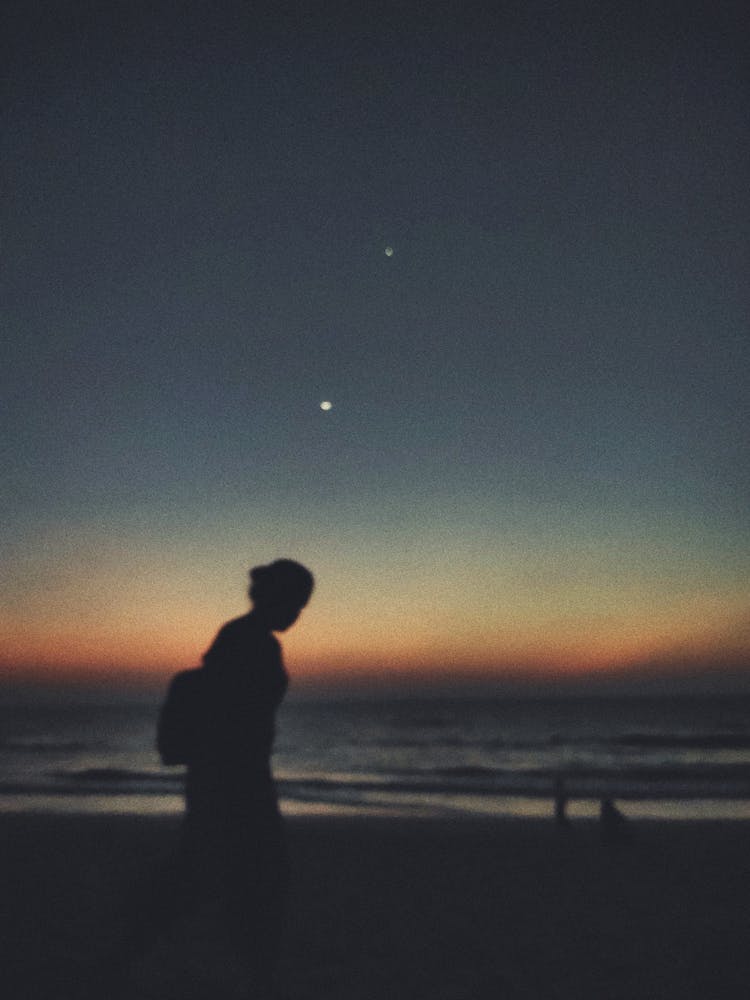 Silhouette Of Woman Walking Near Body Of Water 