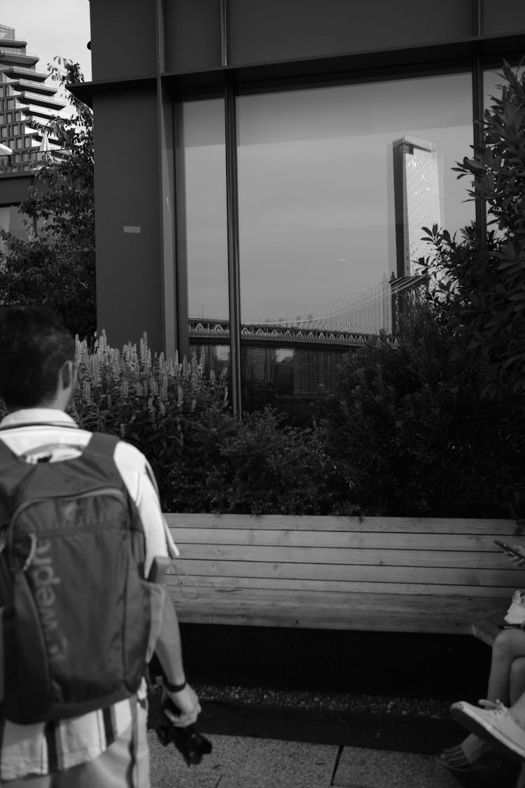 Man With A Camera In His Hand Looking At The Reflection In A Building Window 