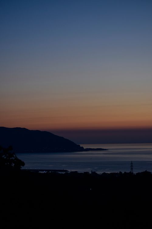 Free Serene twilight image of a silhouetted coastline against a stunning night sky over a calm sea. Stock Photo
