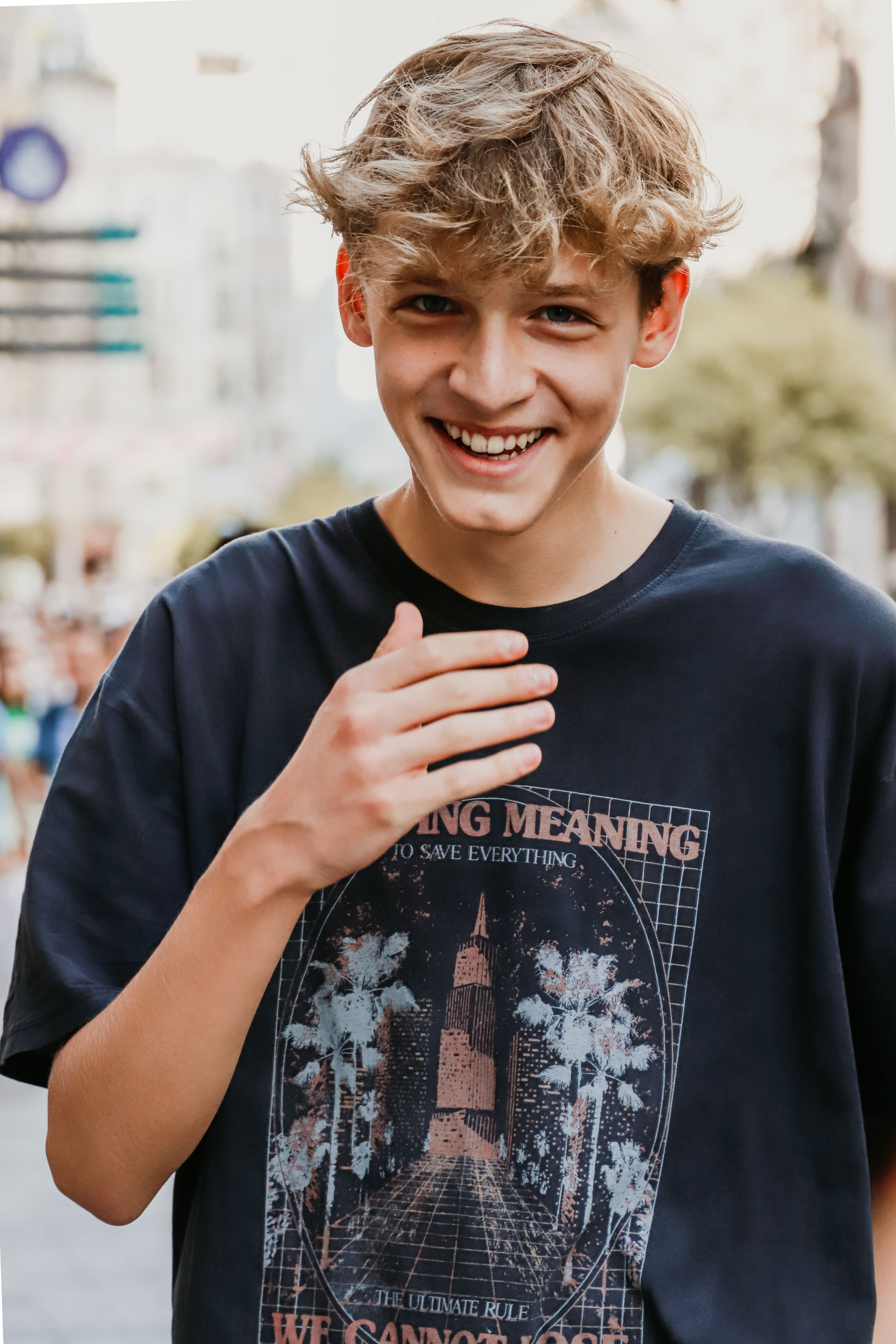 A young man smiles warmly while walking on a bustling street in İstanbul.