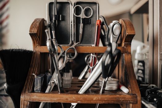 A close-up view of various barber tools on a wooden shelf in a barbershop.