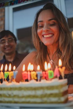 A smiling woman enjoys her birthday with a lighted cake and warm atmosphere.