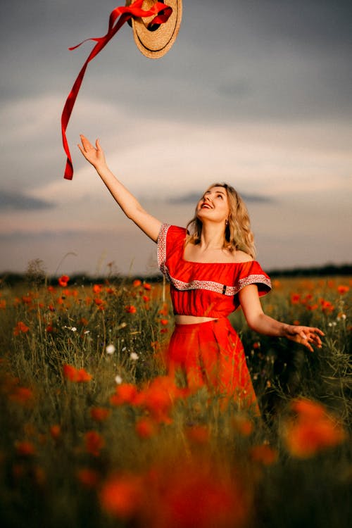 Free Woman in Red and White Dress Standing on Green Grass Field Stock Photo