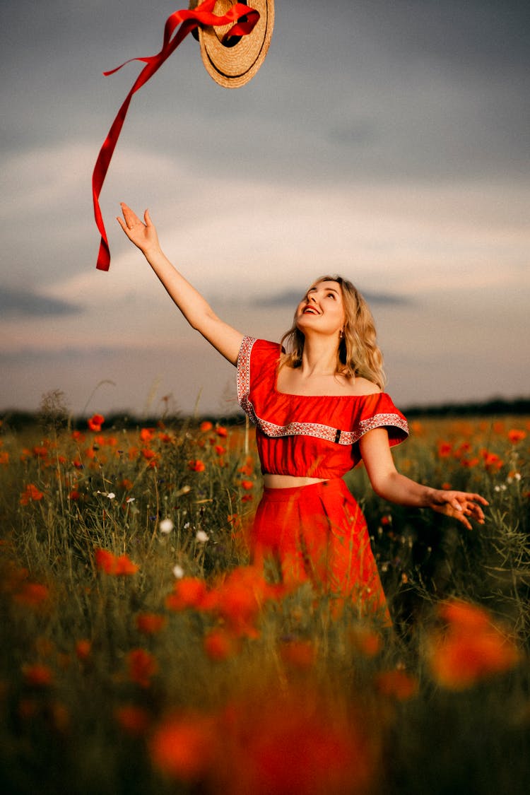 Woman Throwing Hat On Meadow