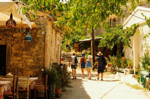 Tourists exploring the rustic charm of Peritheia village in Greece.