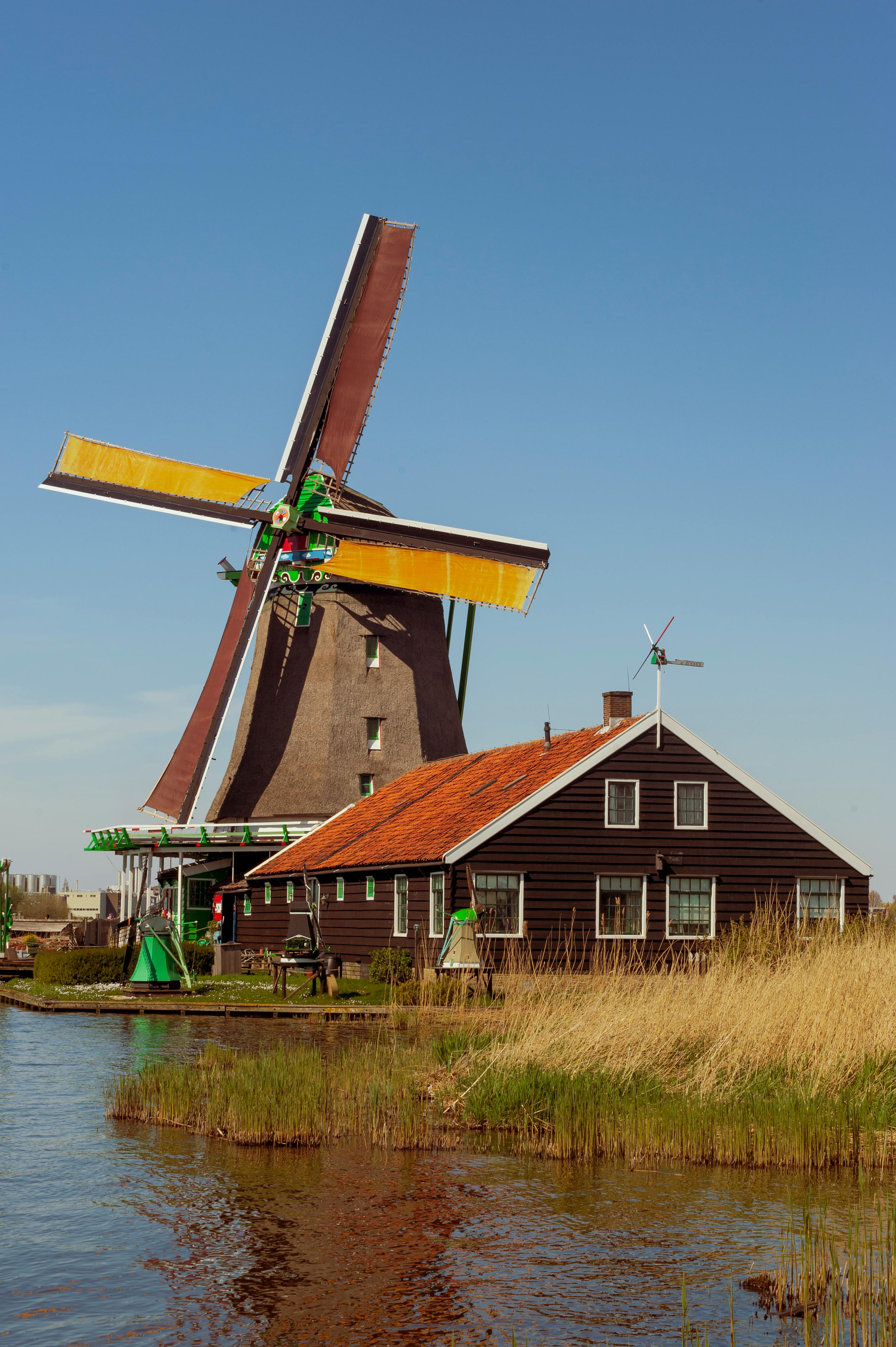 brown and yellow windmill beside the lake