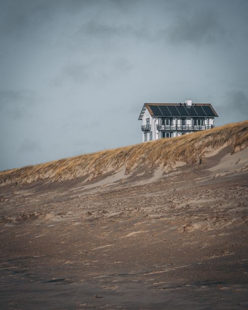 Free Charming beach house atop sandy dunes in Bergen aan Zee with solar panels under a cloudy sky. Stock Photo