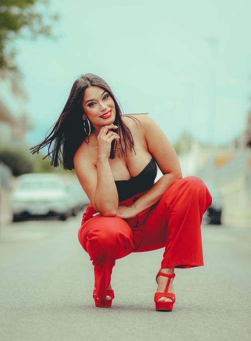 Free Fashionable woman in red pants and heels posing in a city street, exuding confidence and style. Stock Photo
