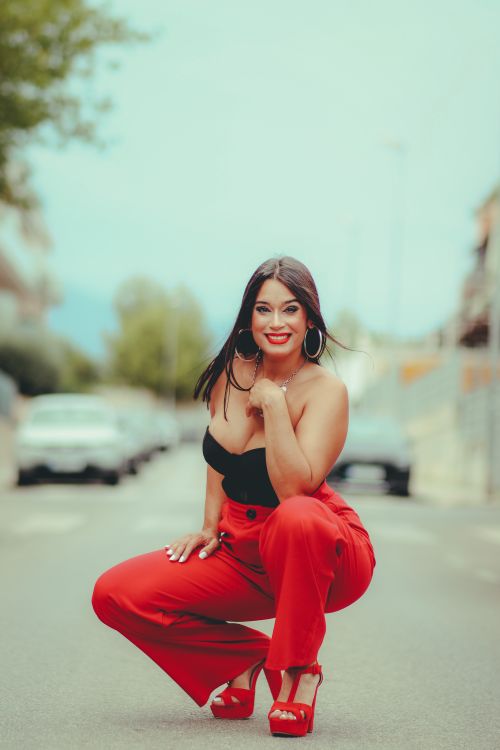 Free A fashionable brunette woman posing with a confident smile on a street, wearing red pants. Stock Photo