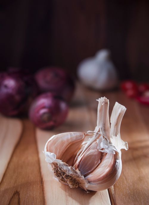 Free Detailed image of a garlic bulb on a wood surface, perfect for culinary themes. Stock Photo