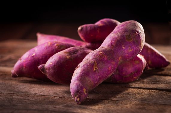 Batatas doces inteiras com casca sobre superfície rústica em close-up