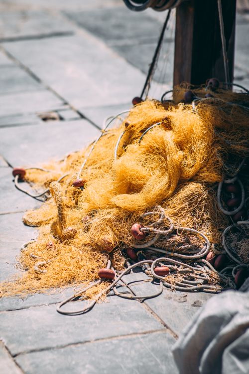 Free Close-up view of a golden fishing net on a stone wharf, bathed in sunlight in Rethimnon, Greece. Stock Photo