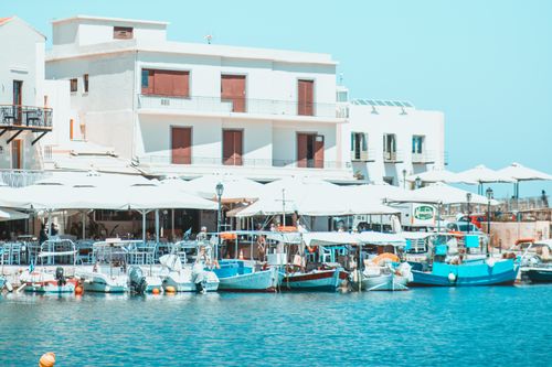 Free Peaceful scene of fishing boats docked by a white building in Rethymno, Greece harbor. Stock Photo