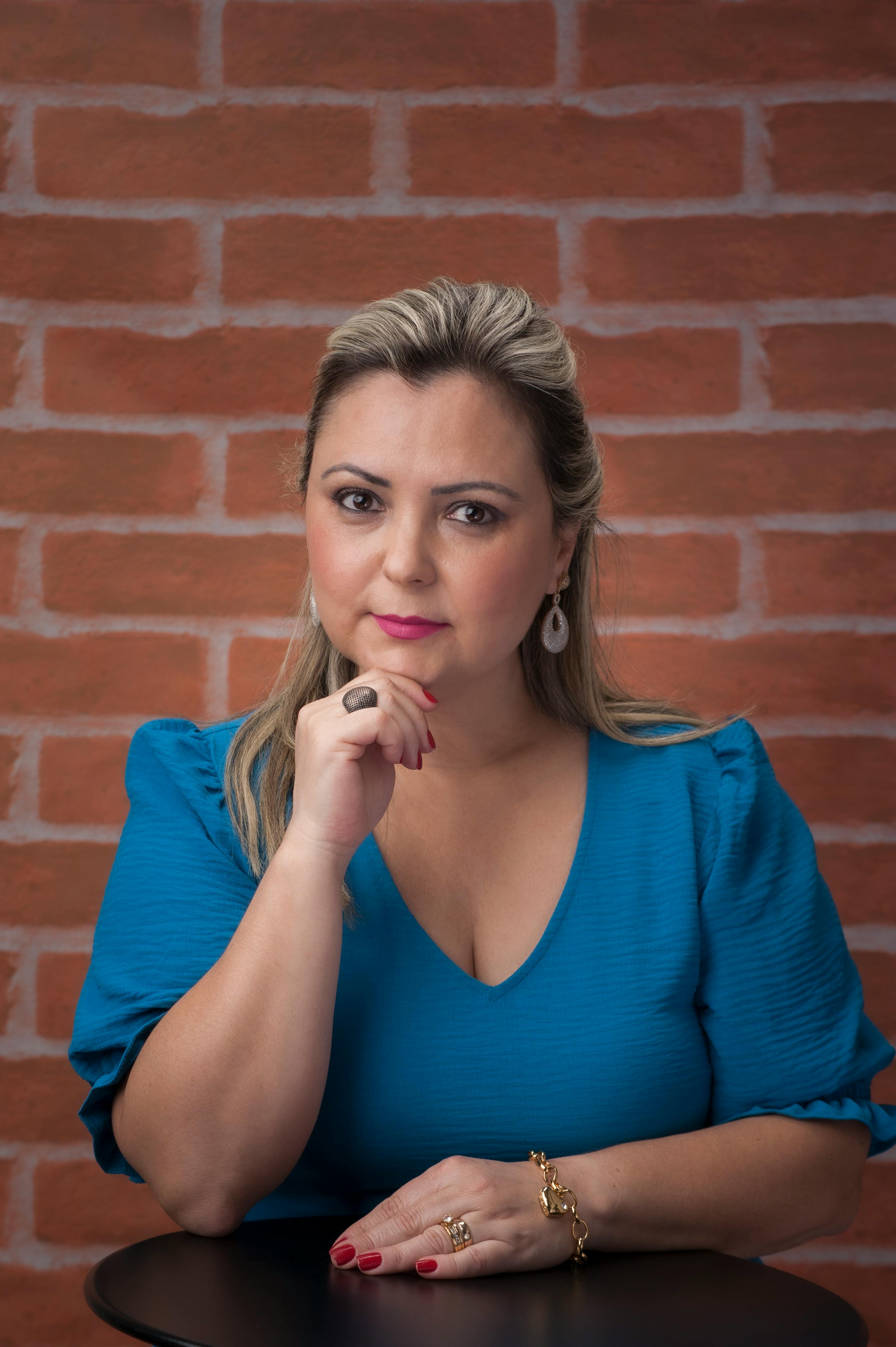 Portrait of a sophisticated woman with blonde hair and stylish jewelry in a blue blouse.