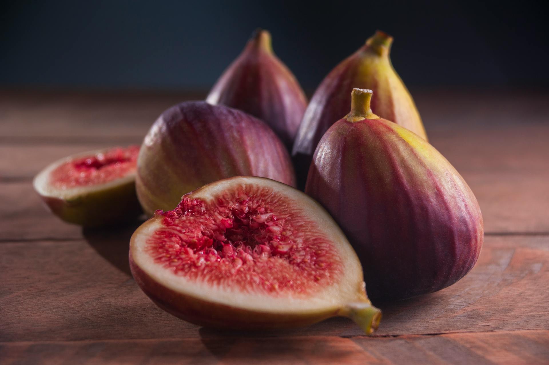 Close-up of ripe figs, whole and sliced, showcasing vibrant textures on a wooden surface.