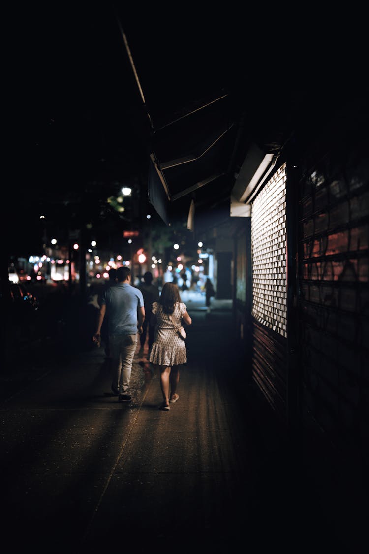 People Walking On Sidewalk During Night Time