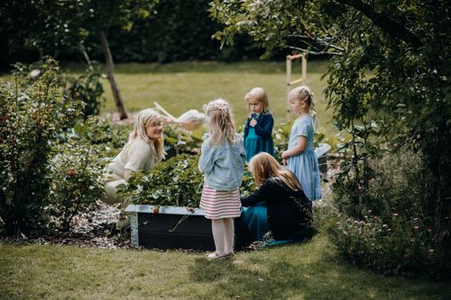 Free A group of children and an adult gardening together in a lush, green backyard setting, enjoying outdoor activities. Stock Photo
