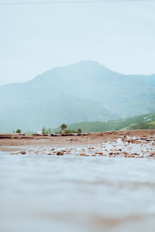 Free Tranquil misty mountain scenery with a clear river in the foreground, showcasing nature's peacefulness. Stock Photo