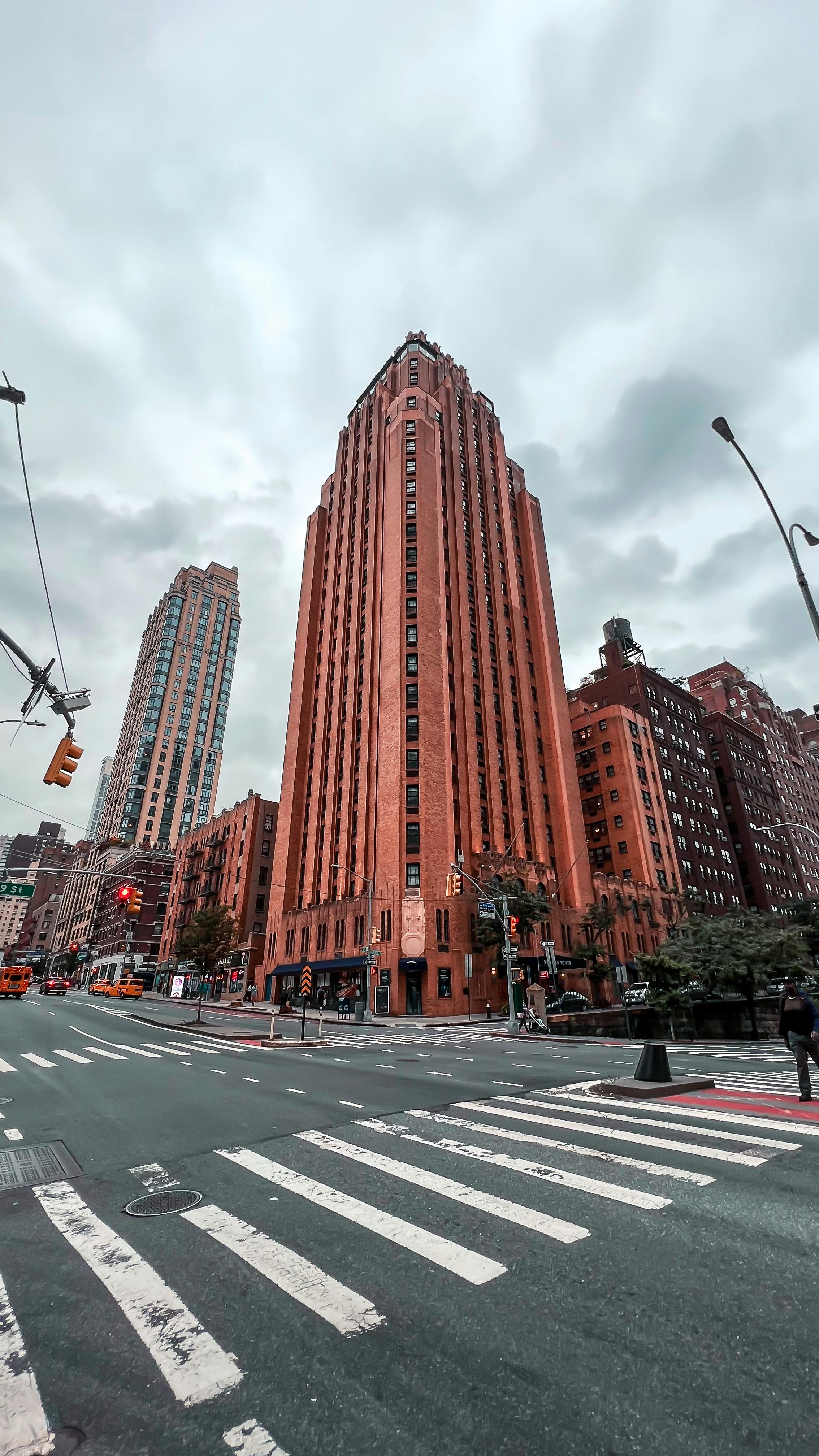 Free Tall buildings on a cloudy day in New York City with pedestrian lanes and traffic lights. Stock Photo