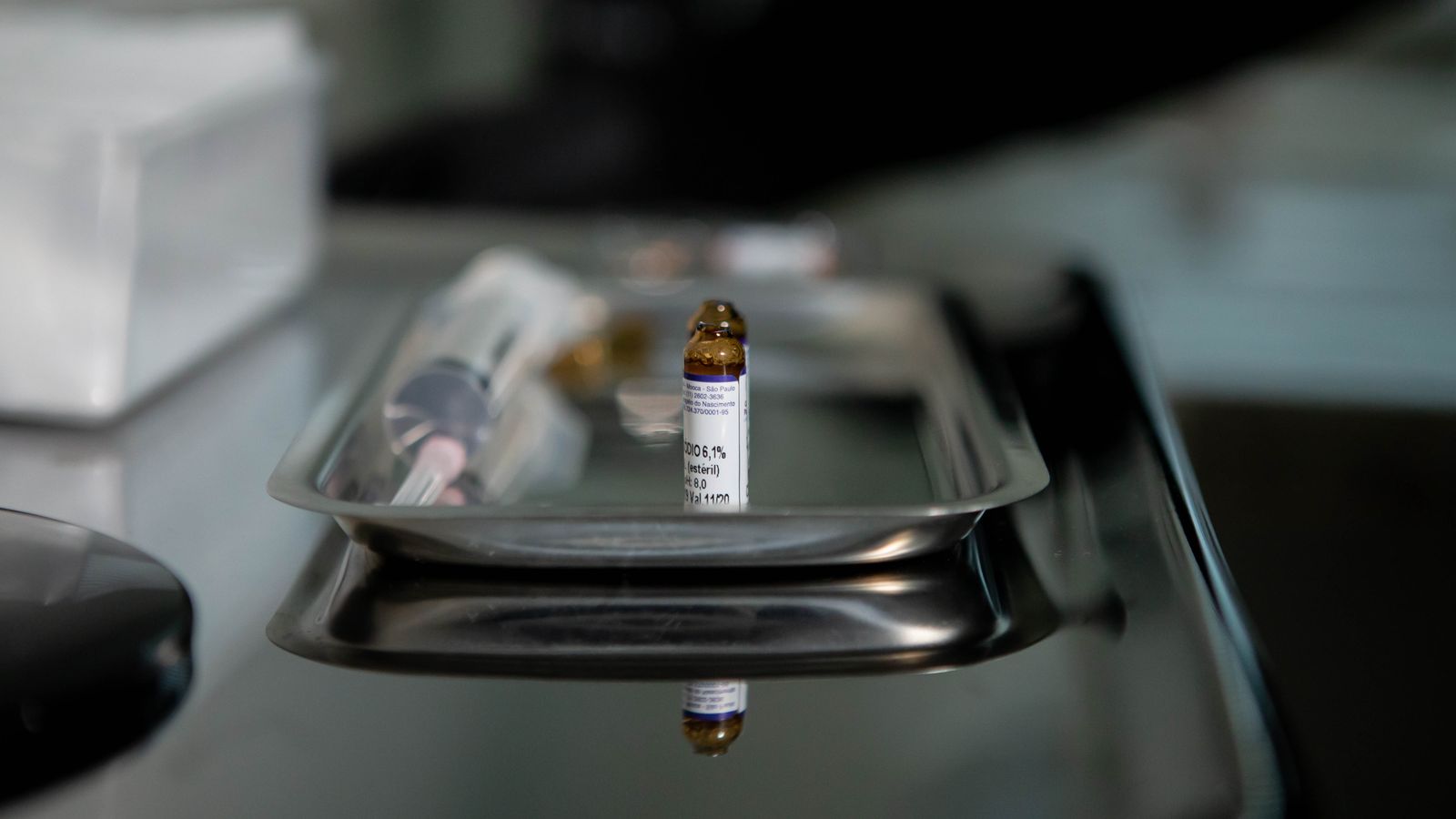 Focus on a vial placed on a stainless steel tray, reflecting a clinical and sterile medical environment.