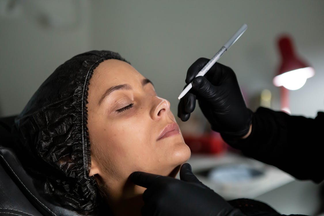 Free Beautician applies skincare treatment to woman's face with precision for enhanced beauty. Stock Photo
