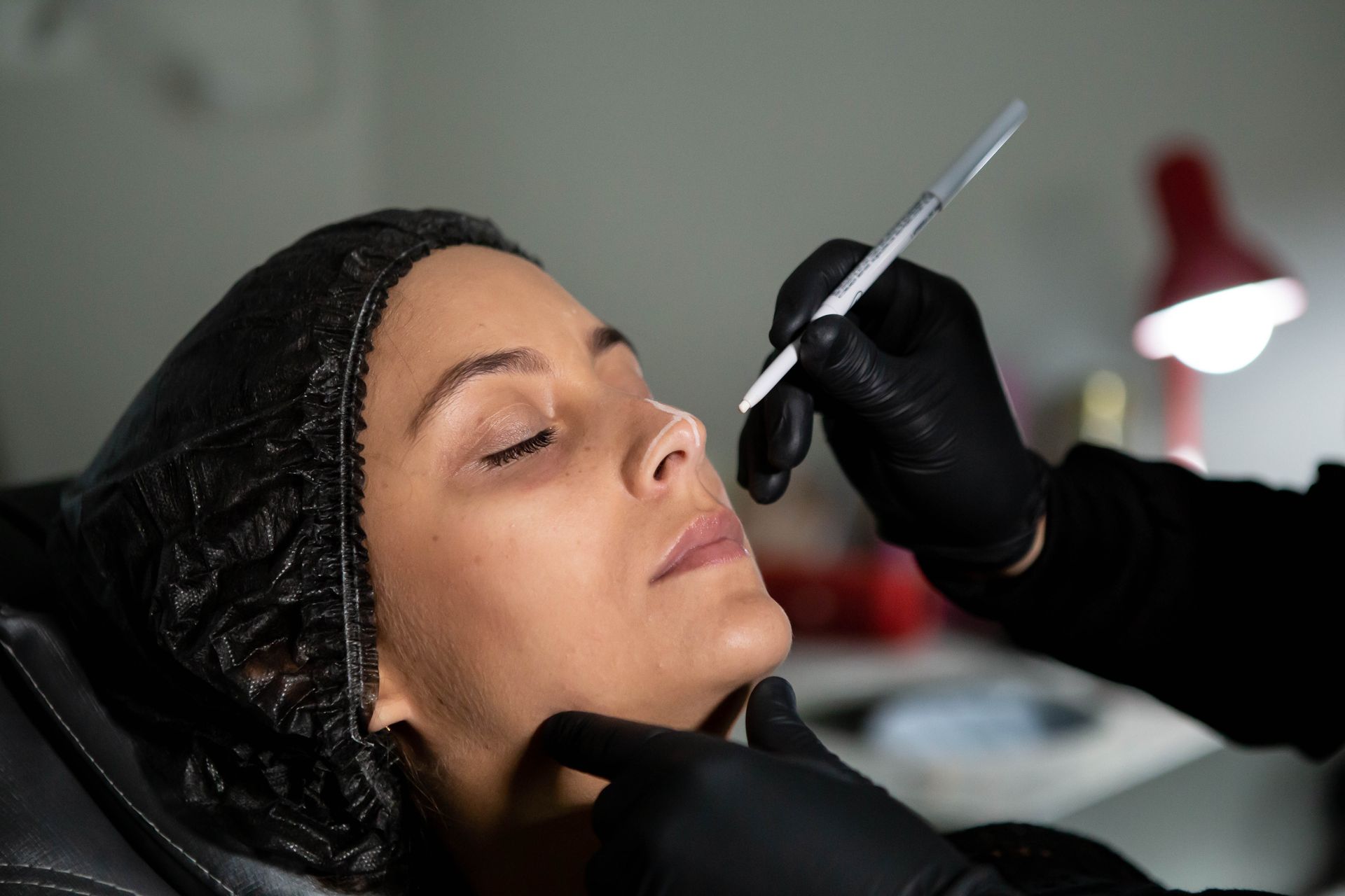 Beautician applies skincare treatment to woman's face with precision for enhanced beauty.