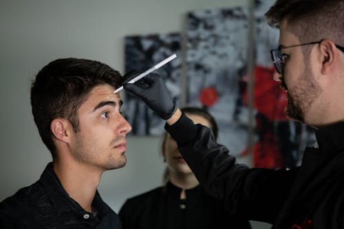 A Man Putting Markings on His Client's Forehead