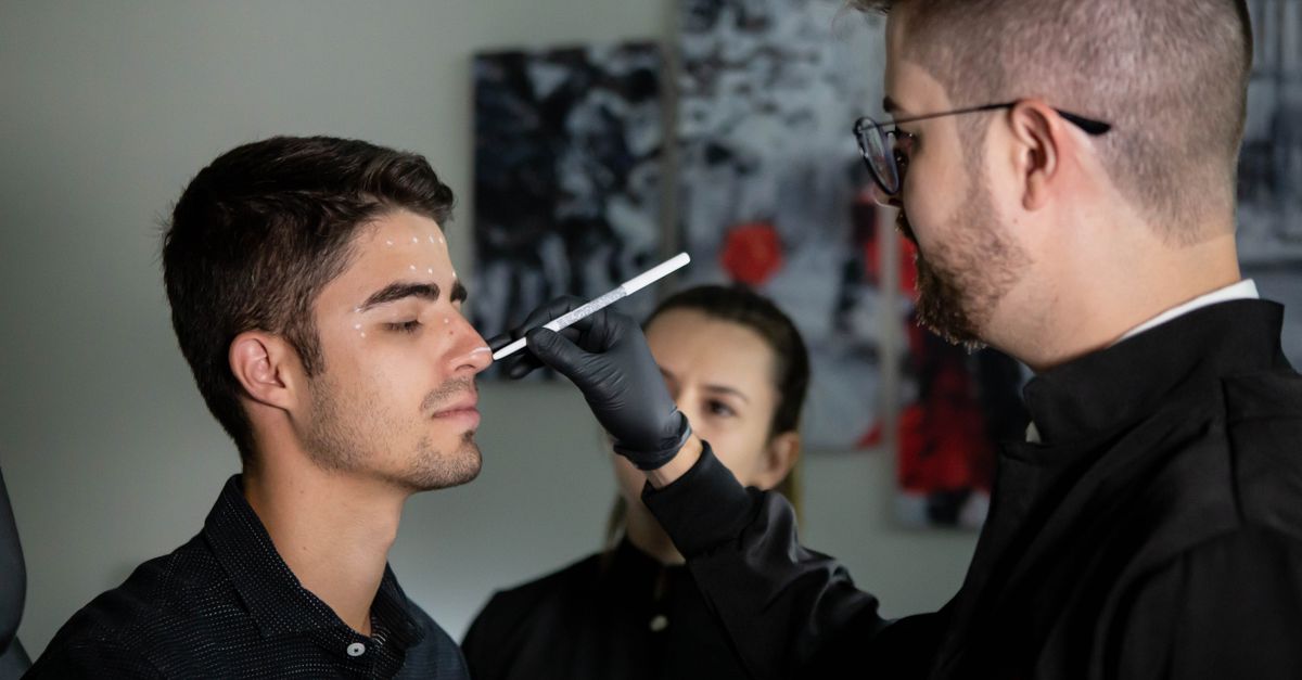 Surgeon marking patient's face for medical procedure in clinic setting.
