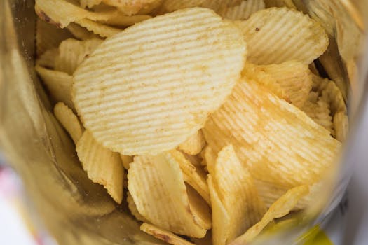 A detailed look at crispy ridged potato chips in an open snack bag, highlighting flavor and texture.