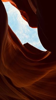 Breathtaking vertical shot of Antelope Canyon's sandstone curves against a clear blue sky.