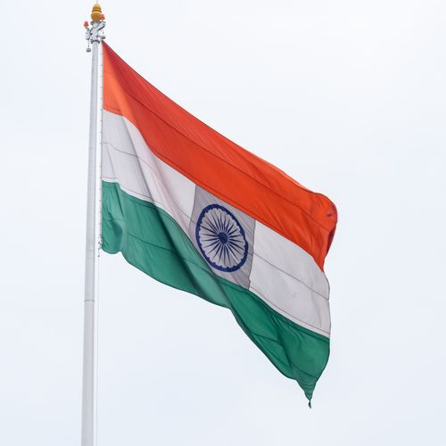 Free Indian national flag waving against a clear sky symbolizing patriotism and pride. Stock Photo