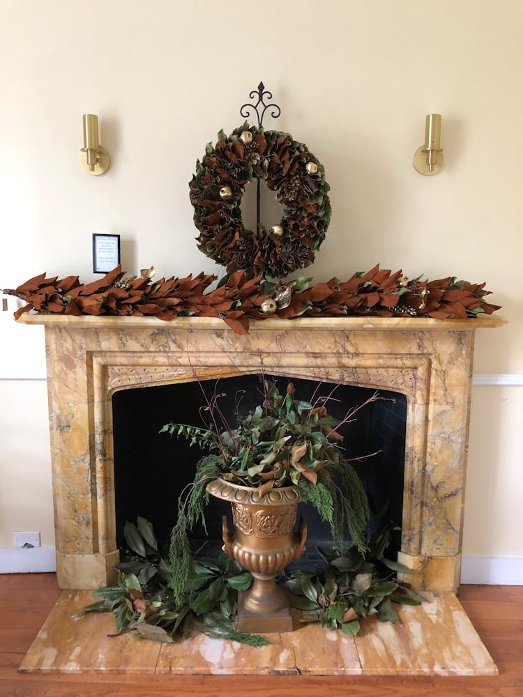 A Brown Pot With Green Leaves By A Fireplace With Christmas Decorations