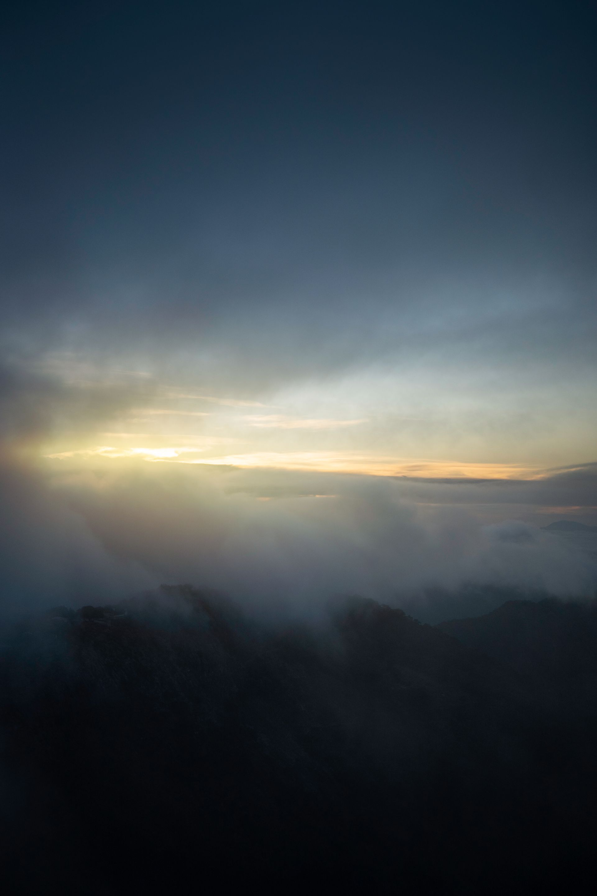 Serene morning with misty mountains silhouetted against a dramatic sunrise.