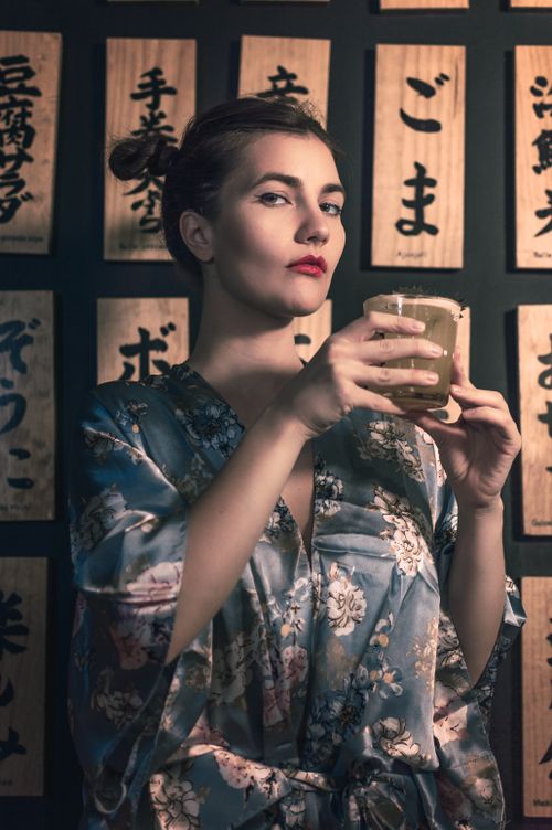 Free A fashionable woman in a kimono holds a cocktail, set against a Japanese-inspired backdrop. Stock Photo
