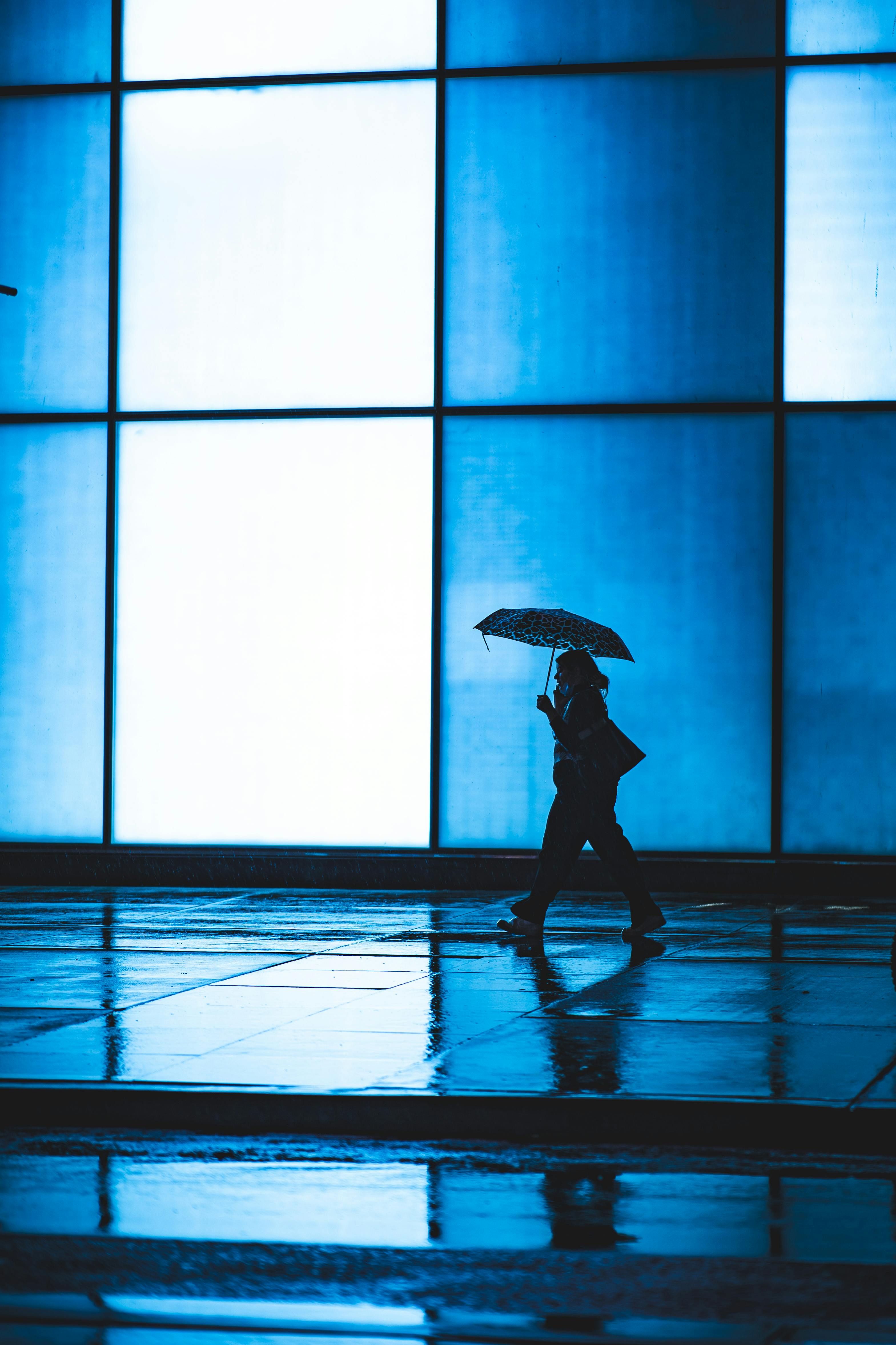 woman holding umbrella walking and talking on mobile phone