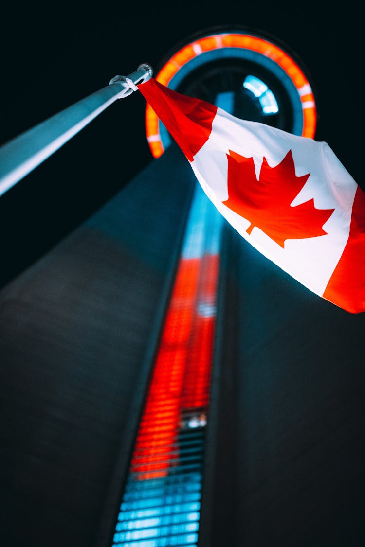 Canadian Flag Before TV Tower In Toronto Canada