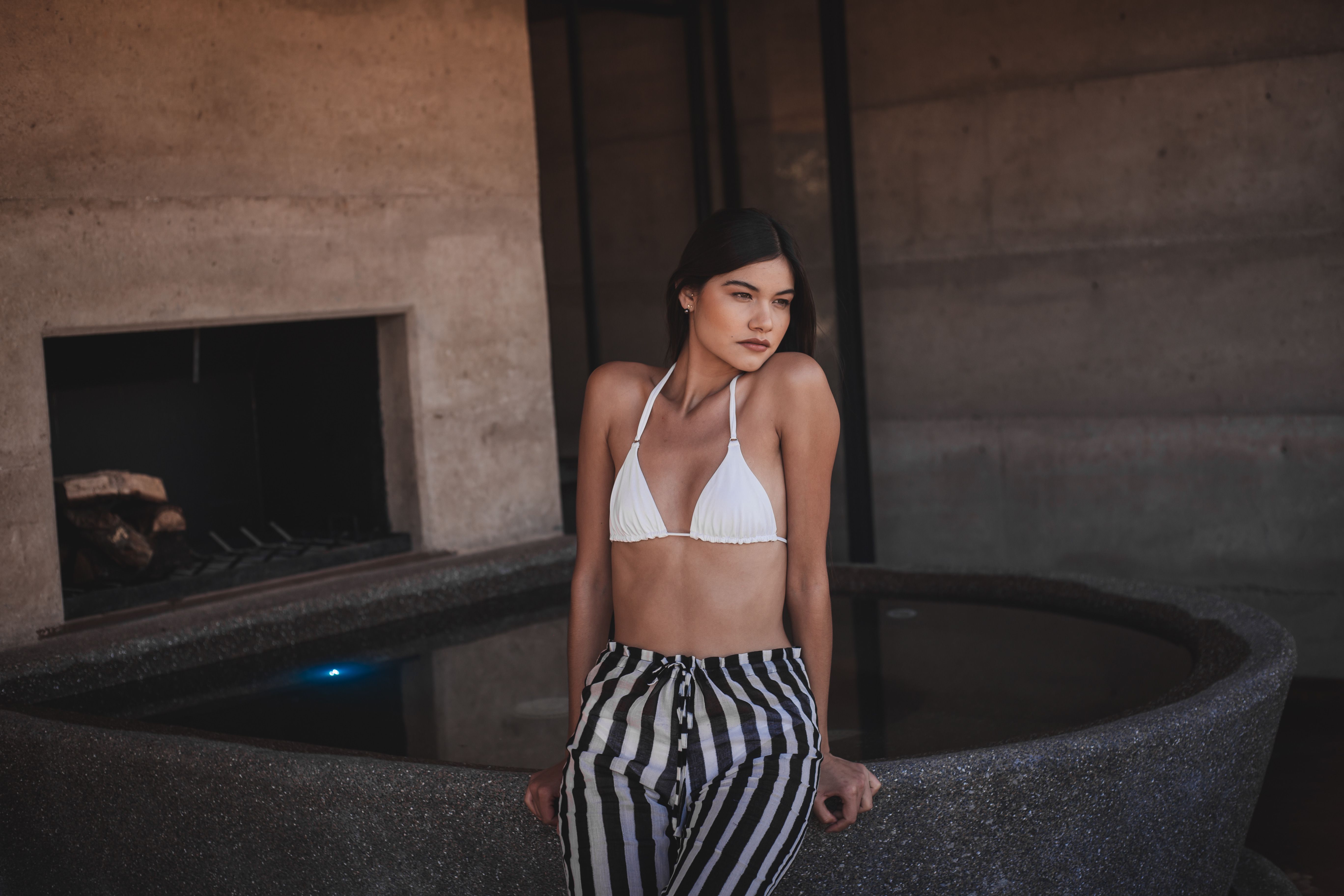 Elegant woman posing by an indoor pool in Guadalupe, Mexico, wearing a stylish swimsuit.