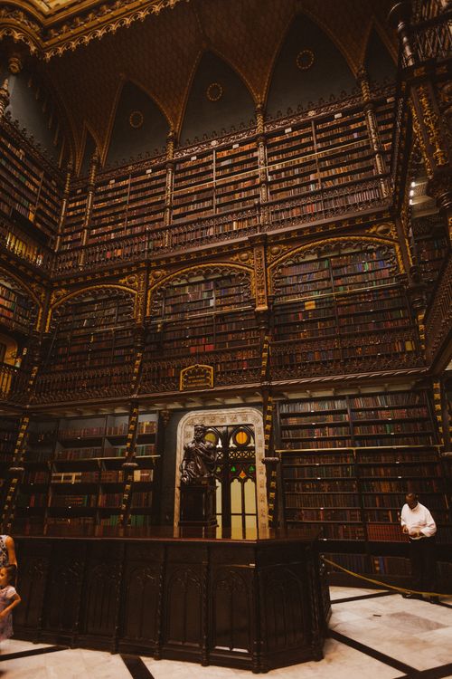 Free Explore an elaborate library featuring towering wooden bookshelves and intricate interior design. Stock Photo